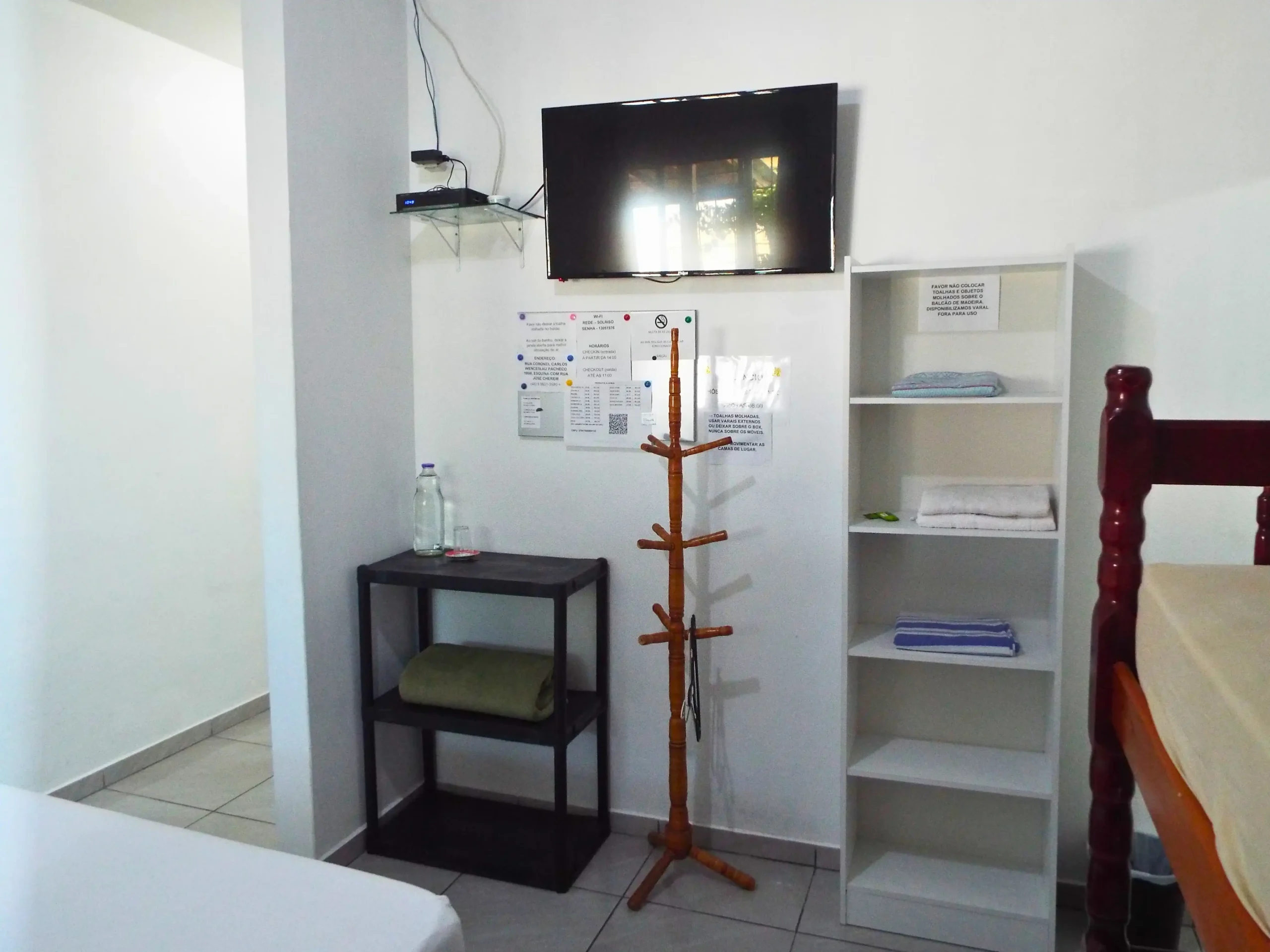 Quarto 10 com uma cama de casal e uma beliche, tv e armario, garrafa de agua, suite com cabideiro
