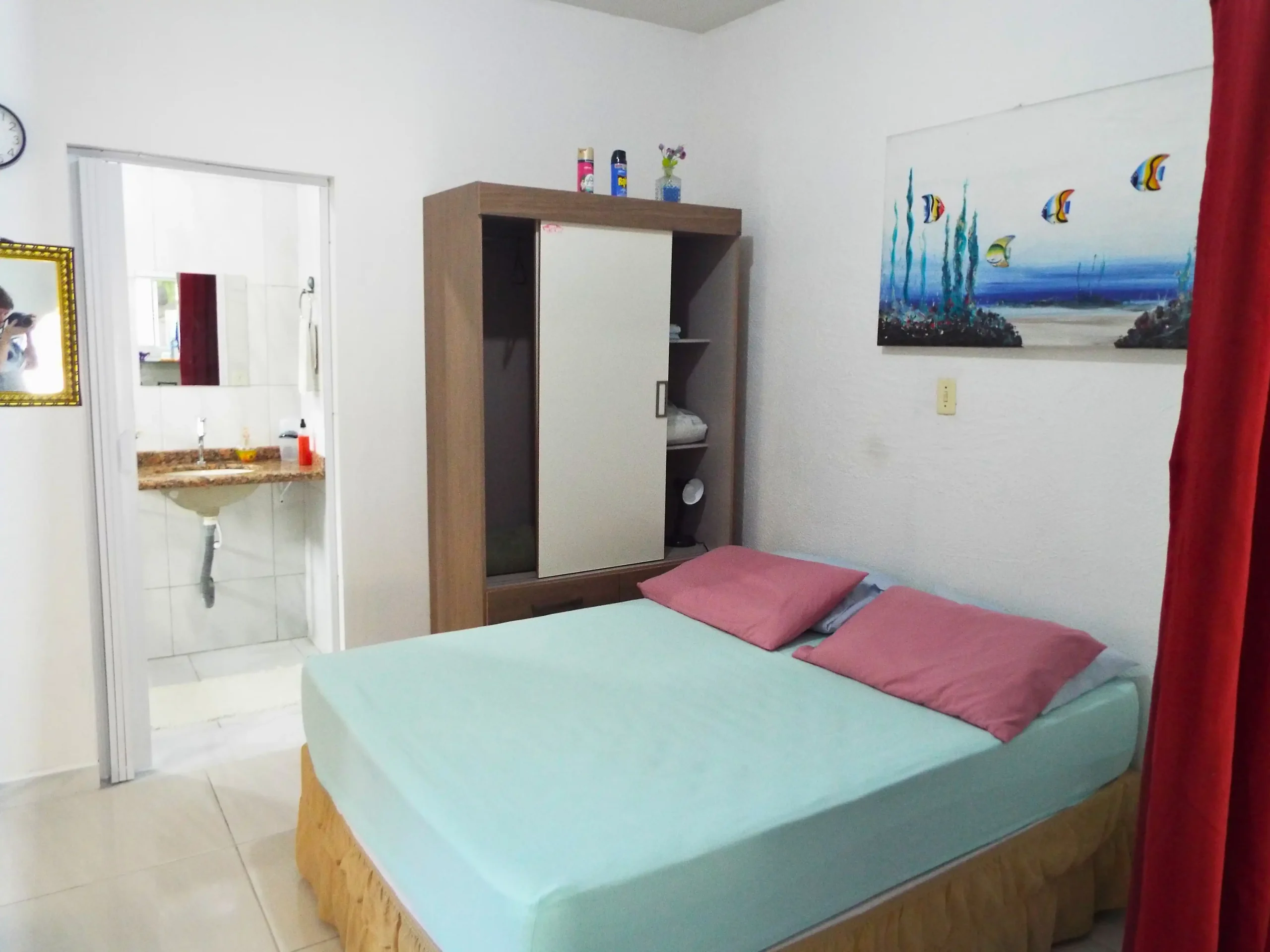 Quarto 6, coma de casal e guarda roupa, tem a presença de luz natural e uma grande pintura de fundo do mar