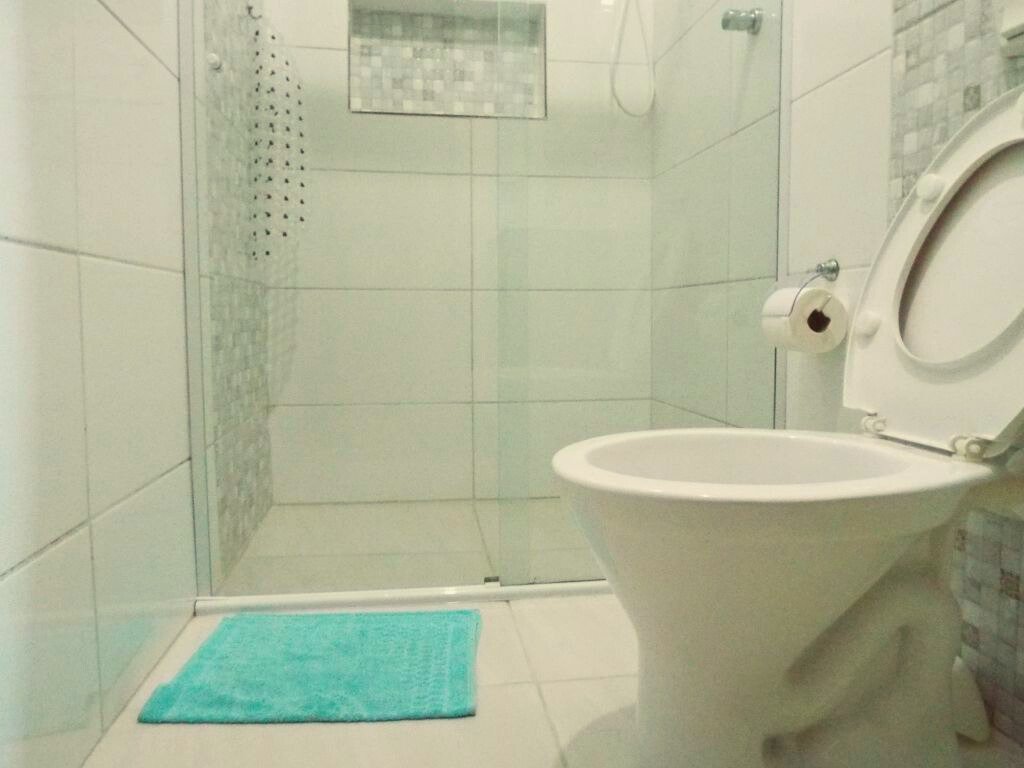 Banheiro do quarto 1 da pousada solriso, com tapete, box, nicho e privada.